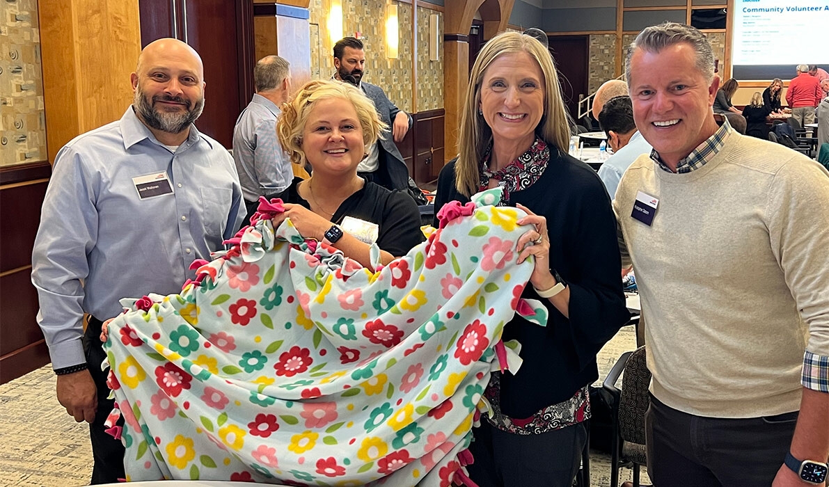 Four Empower associates stand side by side displaying quilt